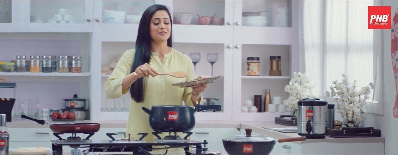 A cook in a white kitchen with PNB Kitchenmate cookware